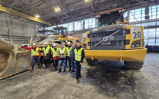 Grupa Studentów na tle dużych pojazdów.